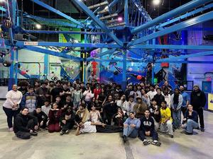 A large group poses together in a colorful indoor entertainment venue.