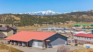 A warehouse with a red roof amidst an industrial park, with mountains in the distance
