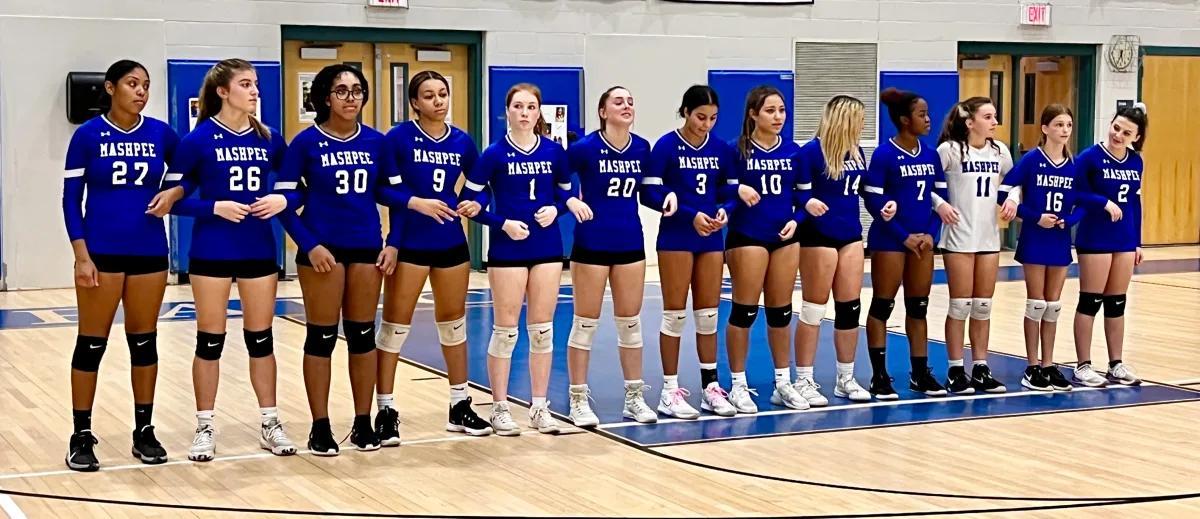 Group of volleyball players in blue uniforms standing in a gymnasium.