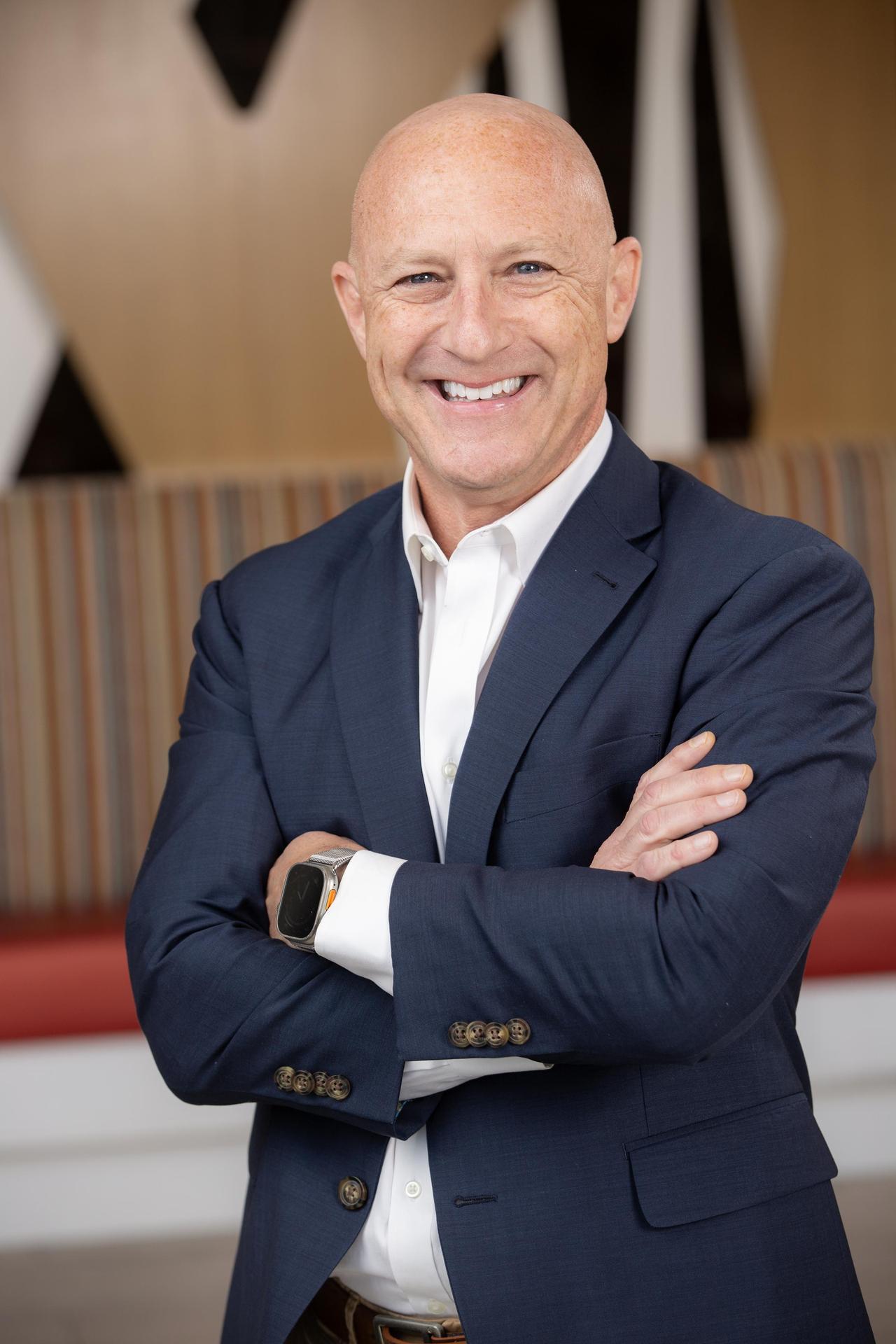 smiling white bald male in a navy suit jacket
