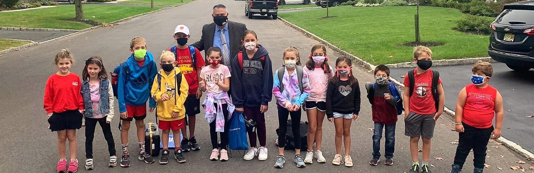 Photo of superintendent posing with students on Walk to School Day