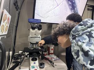 Close-up of a student interacting with a microscope inside the BIOBUS.