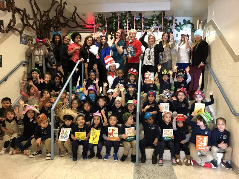 group photo of kindergartners with teachers, aides, and Hudson Administration in the front entryway of the school making funny faces