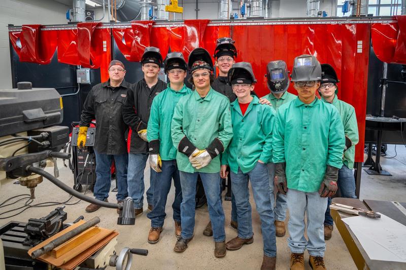 students in welding gear standing in lab