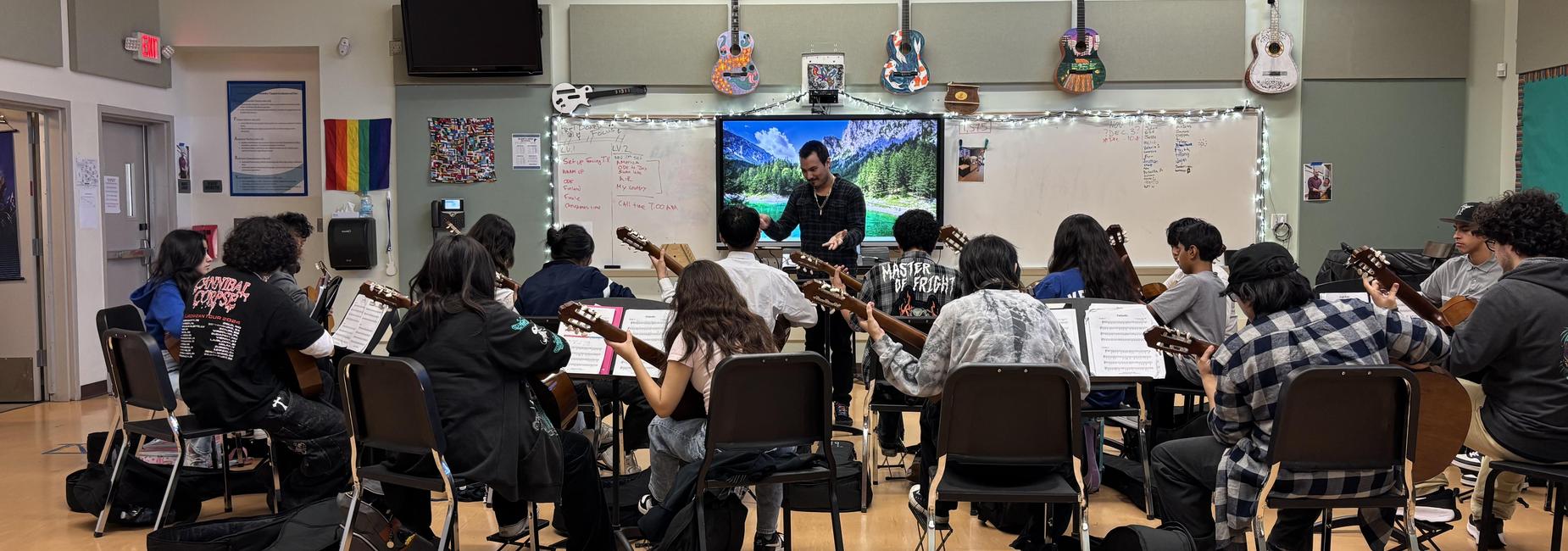 A music class with students playing guitars and a teacher at the front.