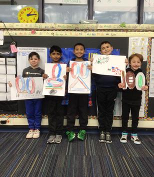 Five children hold posters in a classroom with colorful decorations.