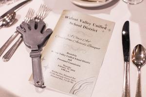 The Cornerstone Banquet Program on a table next to a hand noise-clapper.
