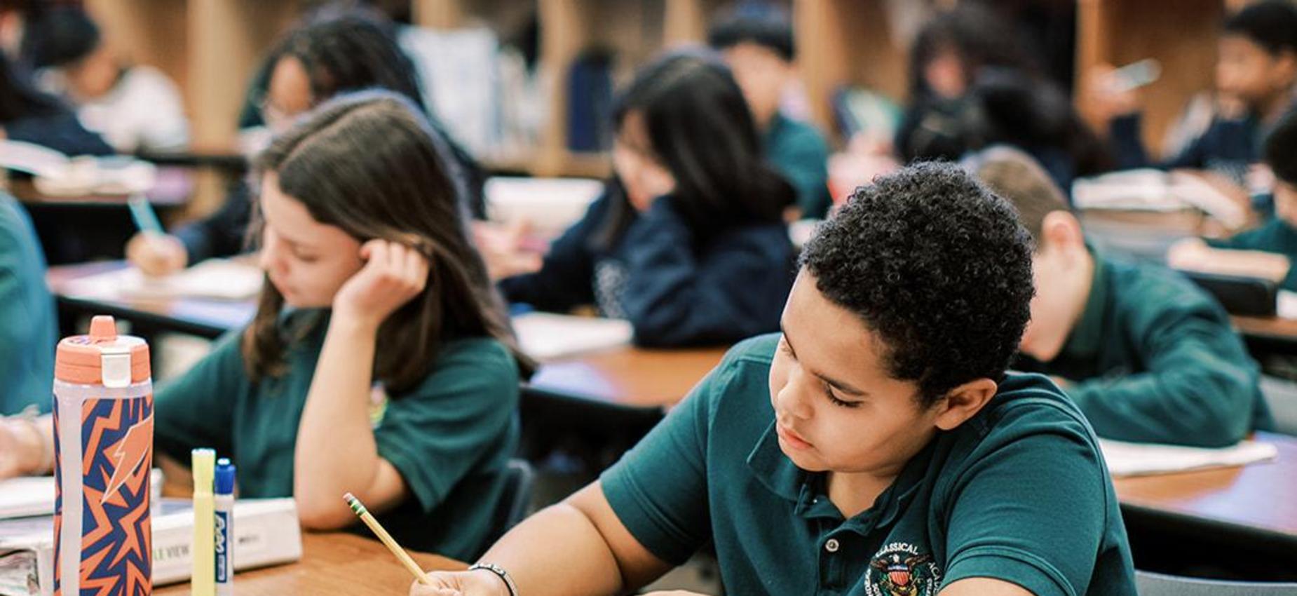 Middle school student writes in his notebook during class
