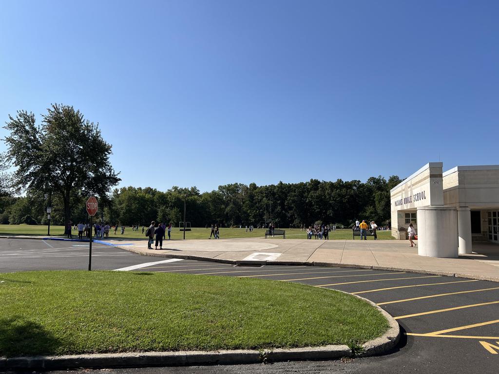 The exterior of the font of the school with students on the lawn in the background.