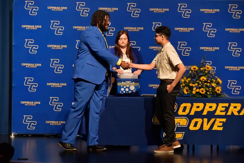 Principal in a suit shaking a student's hand