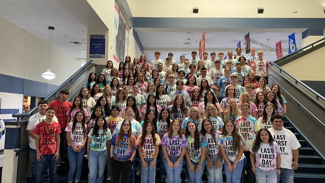 A large group of high school students posing together in matching tie-dye shirts.
