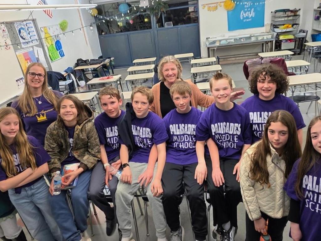 A group photo of students wearing purple Palisades Middle School t-shirts and two teachers.