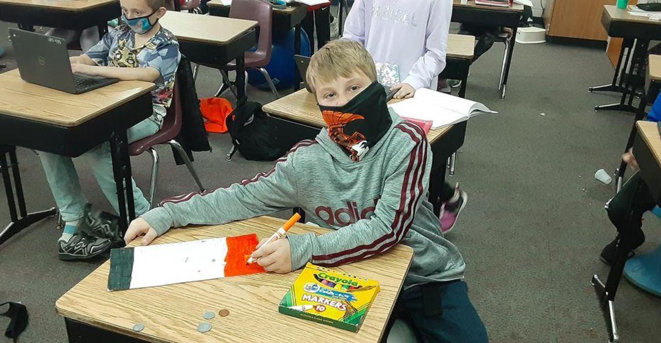 A Page student chooses bright colors to decorate a bag for Kids Food Basket.