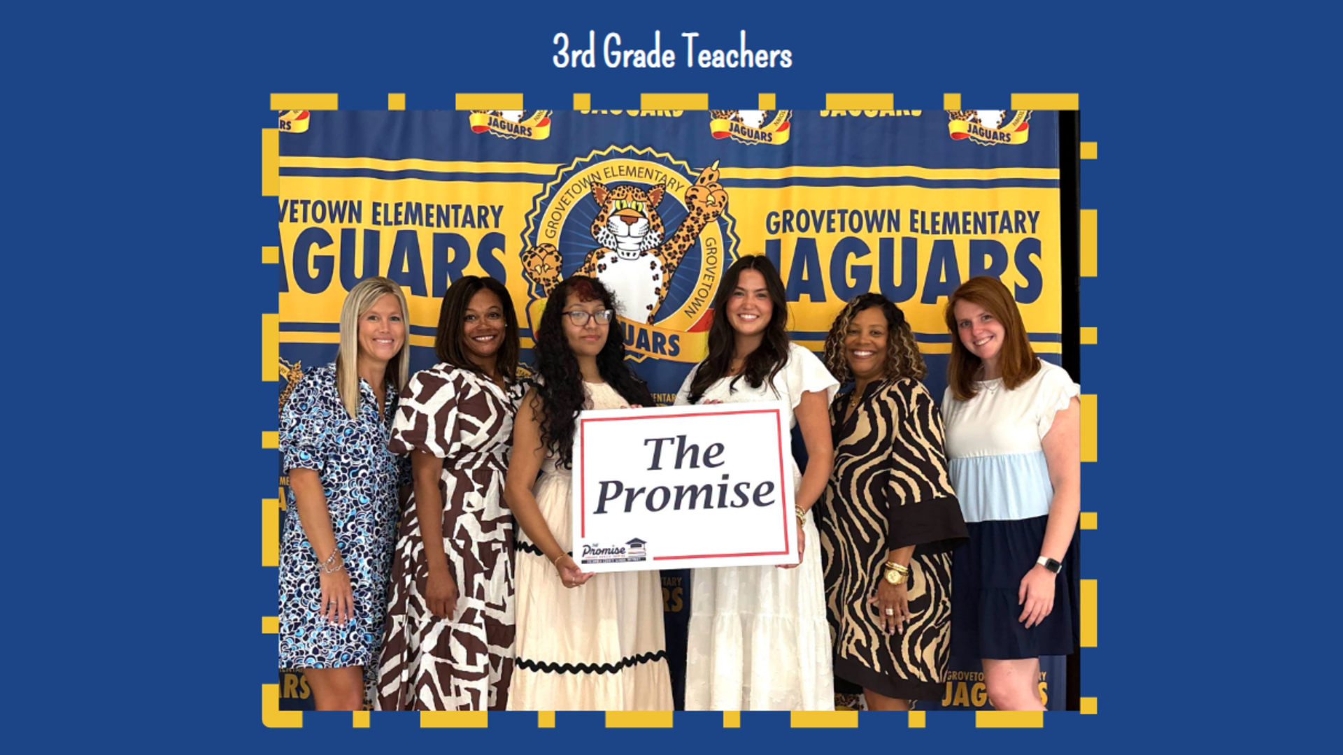 A group of six teachers pose with a sign reading 'The Promise' by a school banner.