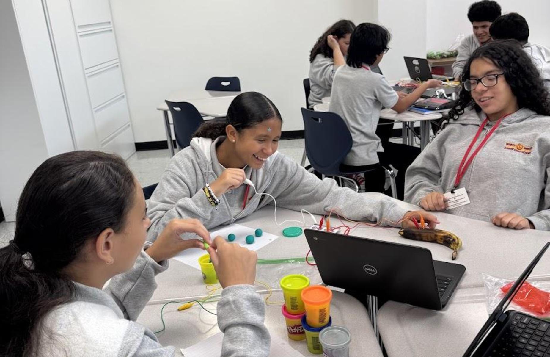 three students working and laughing. THey are using circuits