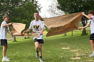 8th-grader Blake Telenko crosses the finish line while two other students hold a big sign