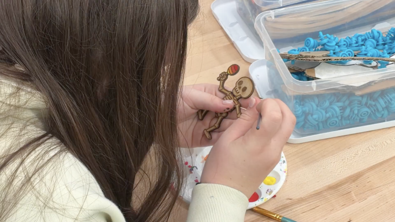 A Miller Middle School student paints fine details onto a laser-cut skeleton figure for Día de los Muertos.