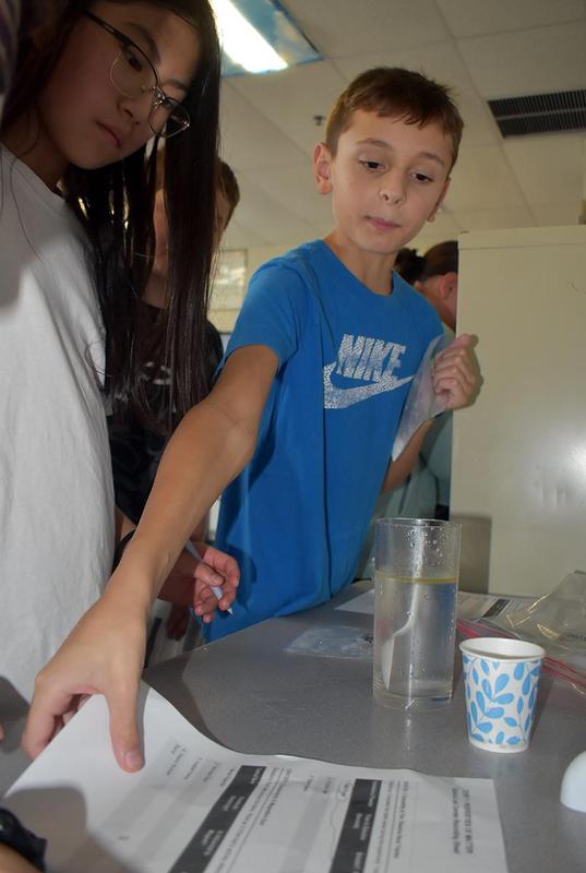 A boy reaching for a paper while participating in a group activity with others.