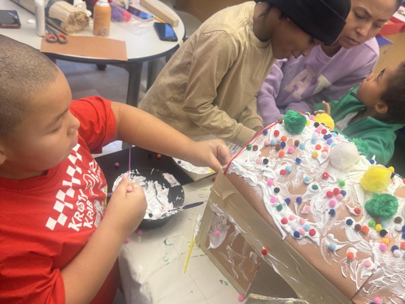 Students and teacher building a gingerbread house