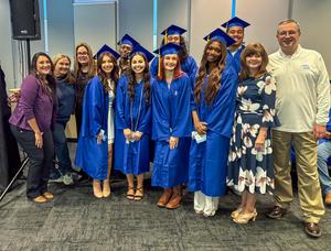 A group of students in graduation caps and gowns with teachers