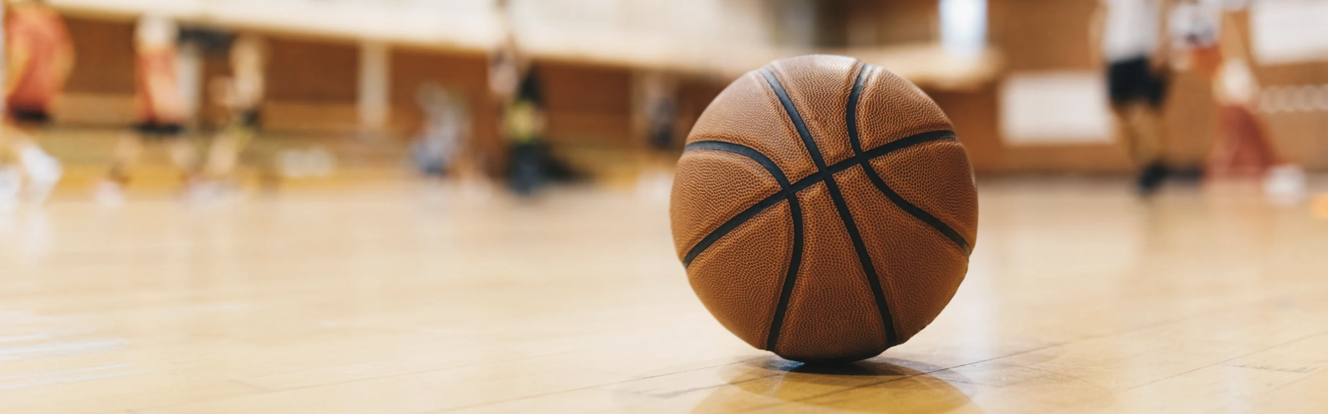 A basketball resting on a wooden gym floor