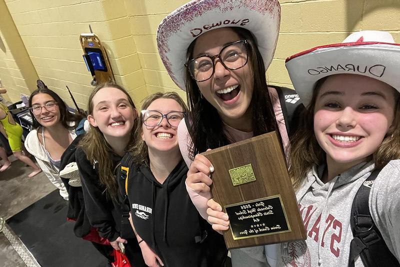 Five delighted members of a high school swim and dive team hold their coach's award.