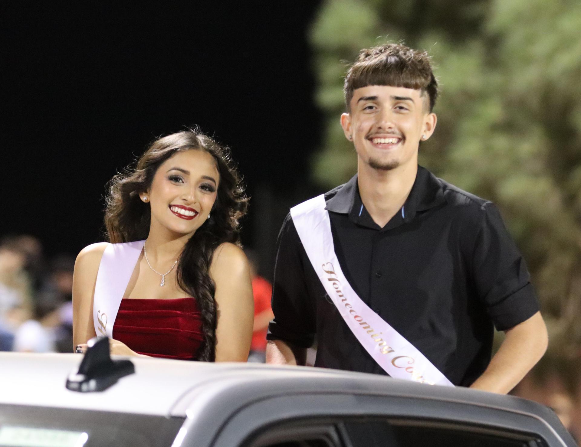 homecoming king and queen candidates entering the stadium in trucks