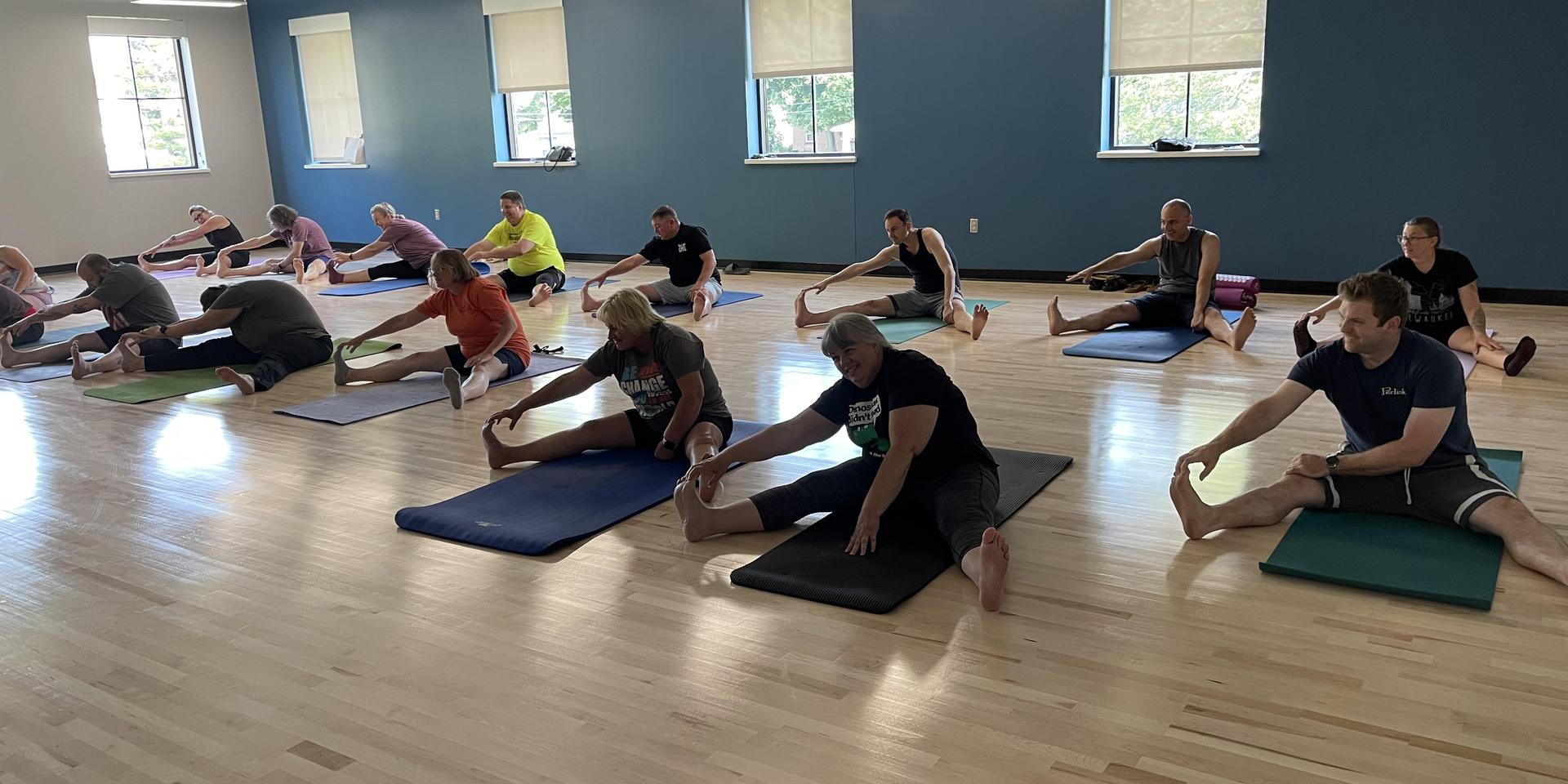 Group of people stretching in a spacious fitness studio.