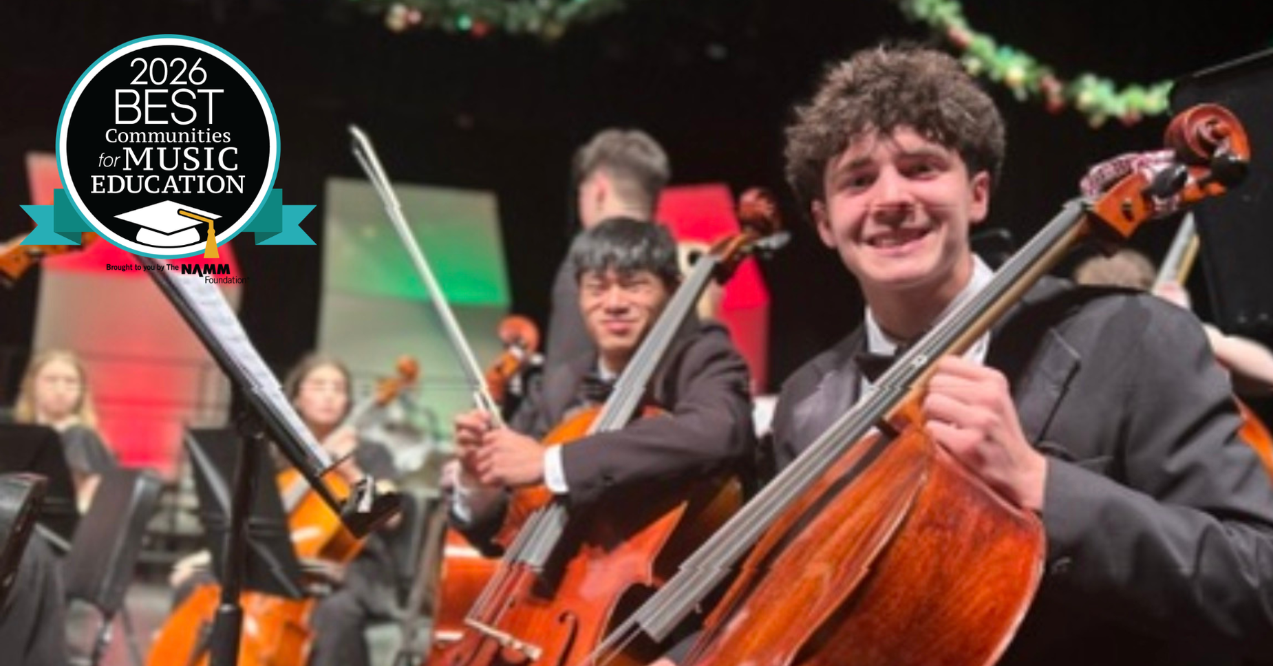 Students playing cellos during a concert with an award logo in the corner.