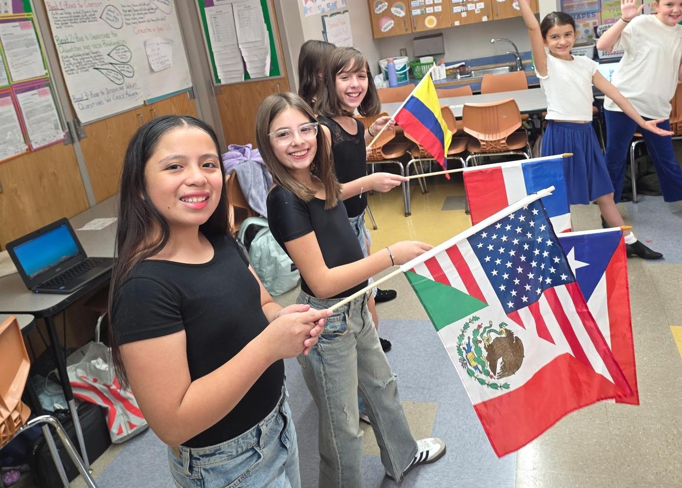 students lining up wearing black tops and blue jeans holding hispanic country flag