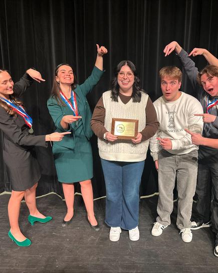Group of people celebrating a winner holding an award on stage.