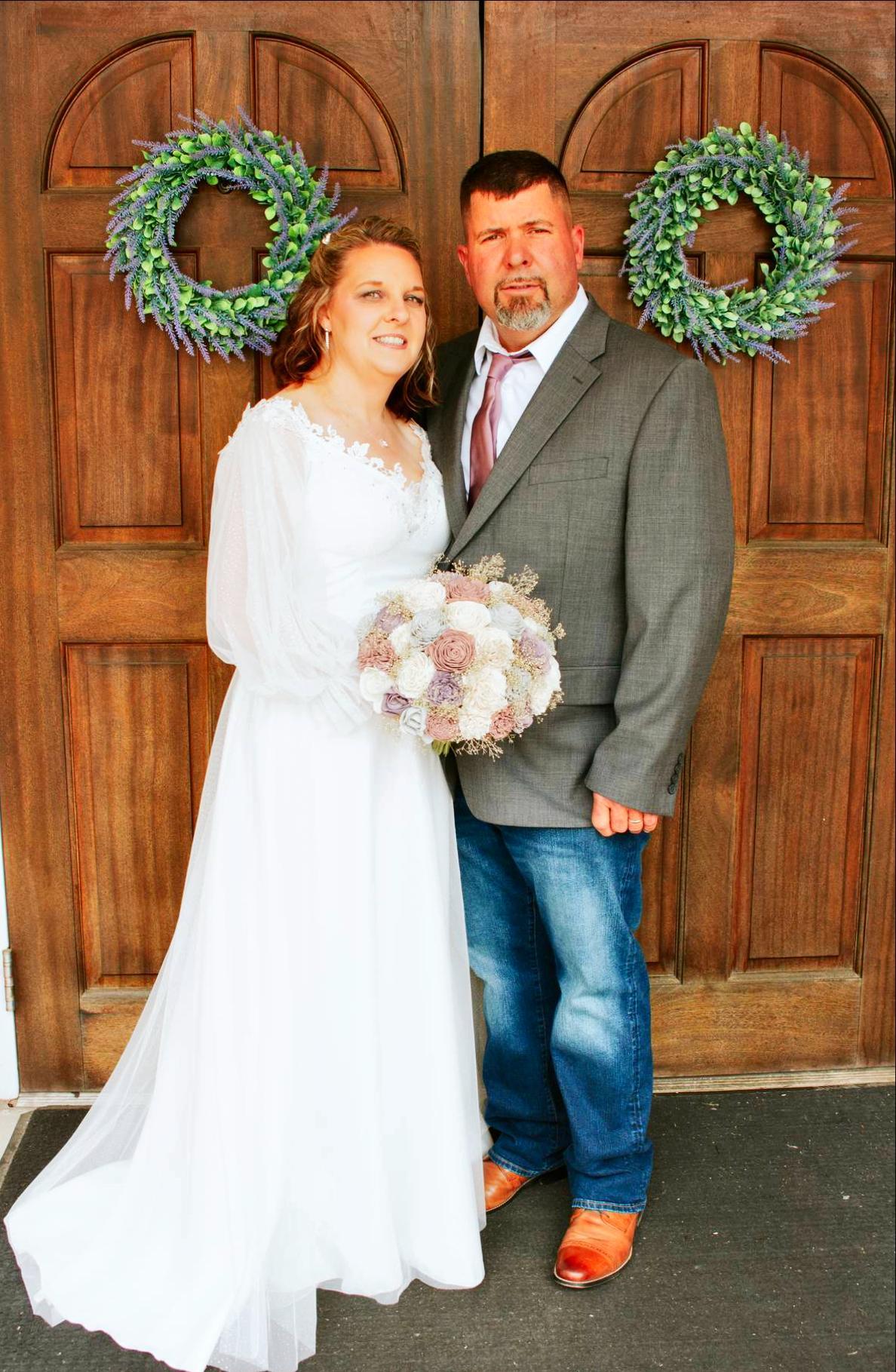 Man and woman in front of a door in wedding attire. 