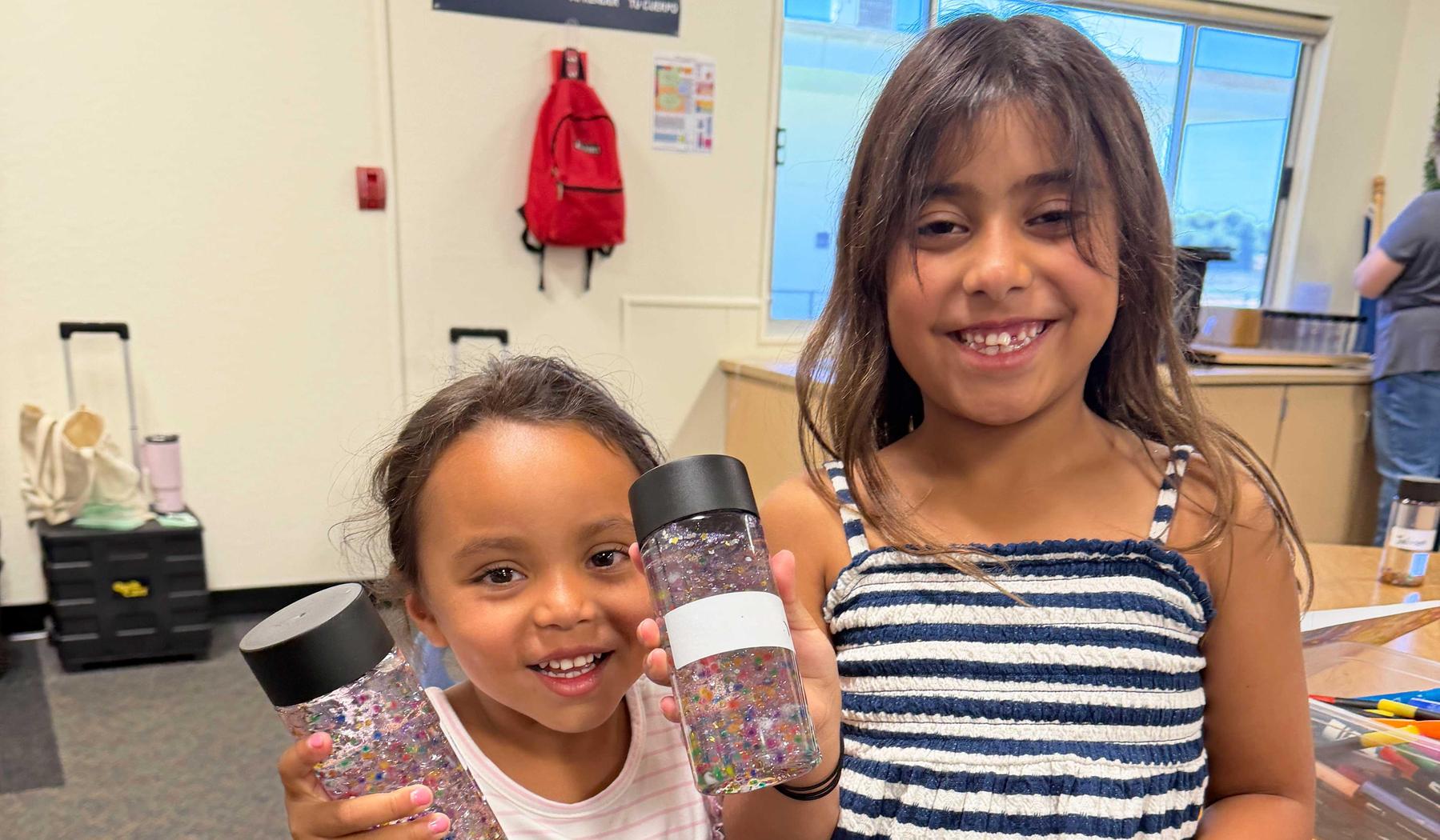 two girls holding jars of glitter
