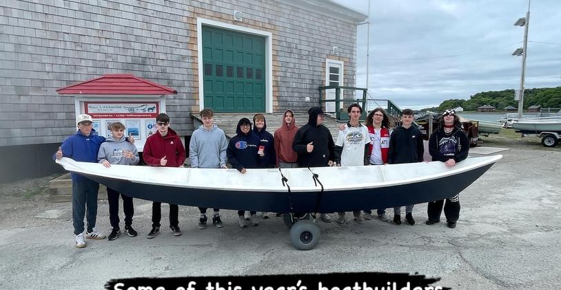 Group of students posing with a boat they built together.
