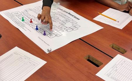 A hand moving a game piece over a board game layout on a table.