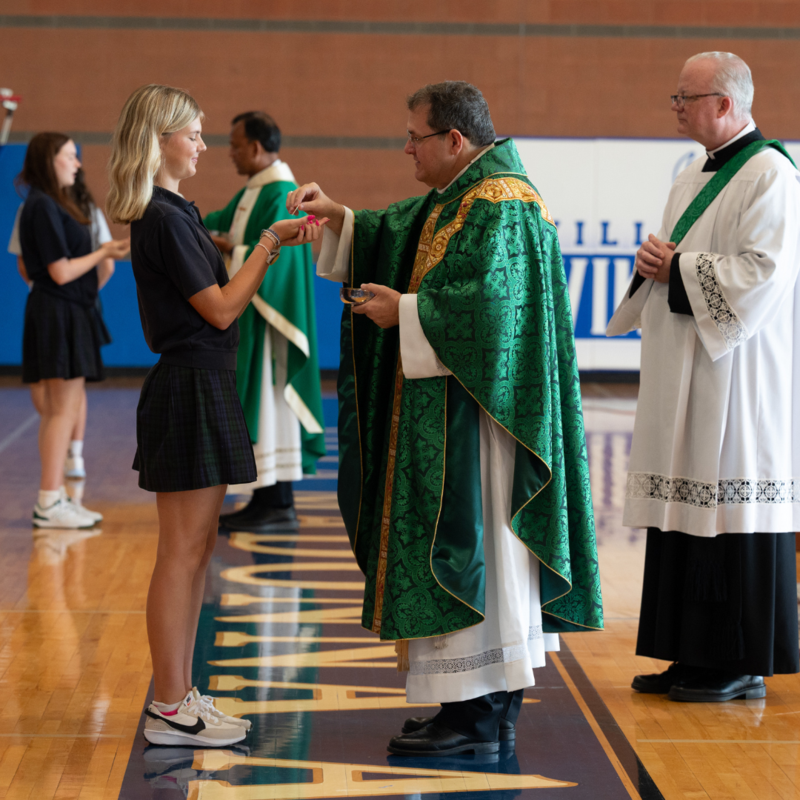 The Bishop gives Holy Communion to a student.