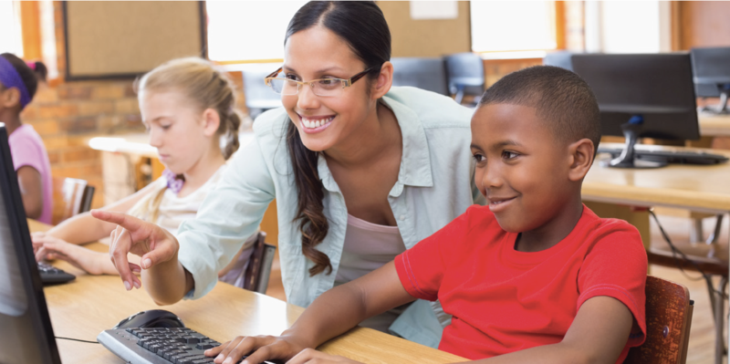 teacher helping student at computer