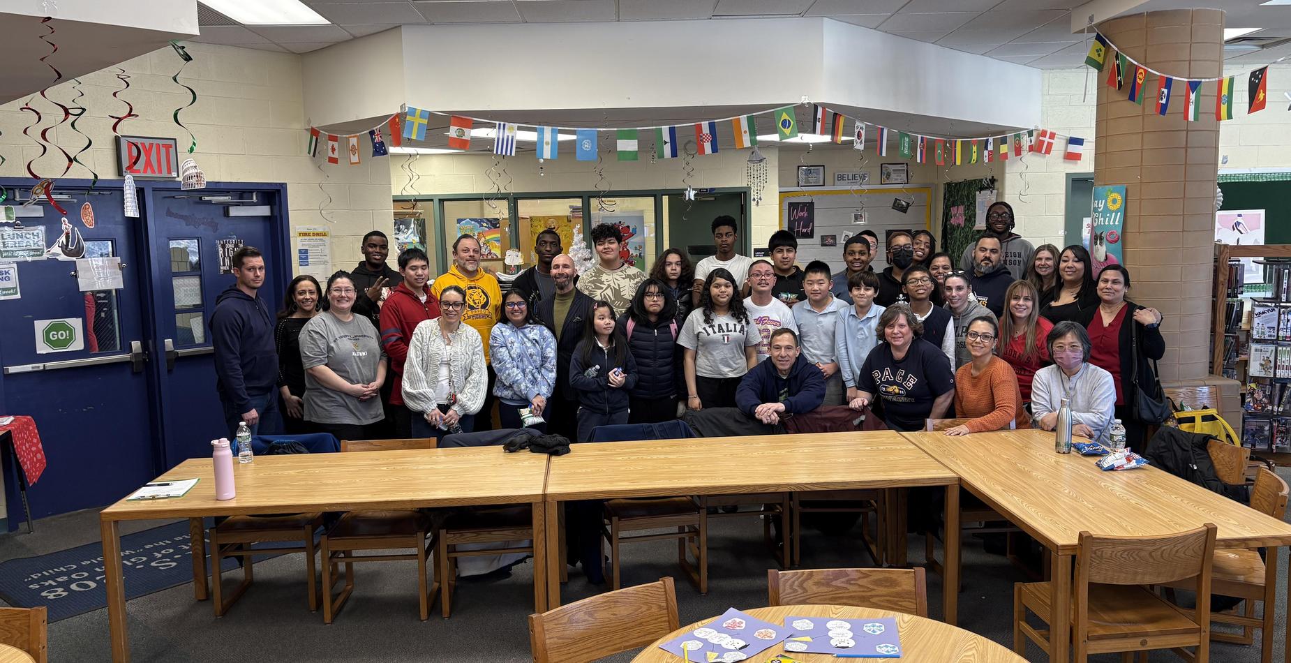 A large group photo of diverse individuals gathered in a library setting.