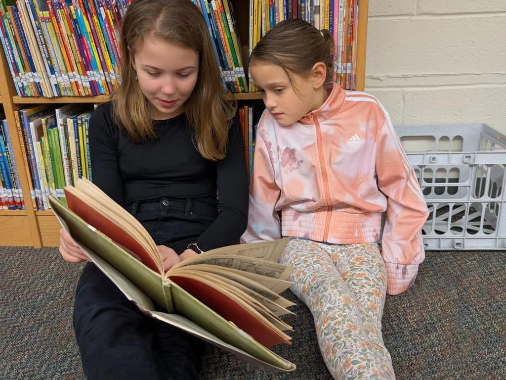 Two students reading to one another in the library.