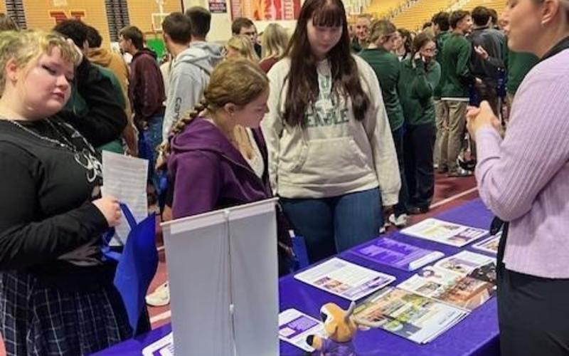 Cheerleaders in red and white uniforms posing together with pom-poms outdoors.