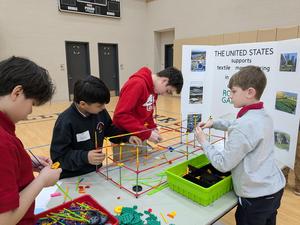 Children collaborate to build a structure with colorful construction materials.