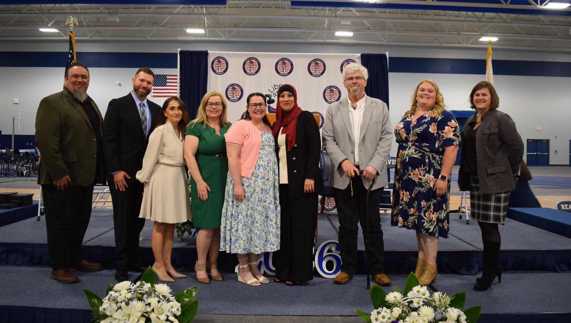 Group of educators and administrators gathered on stage at a graduation event.