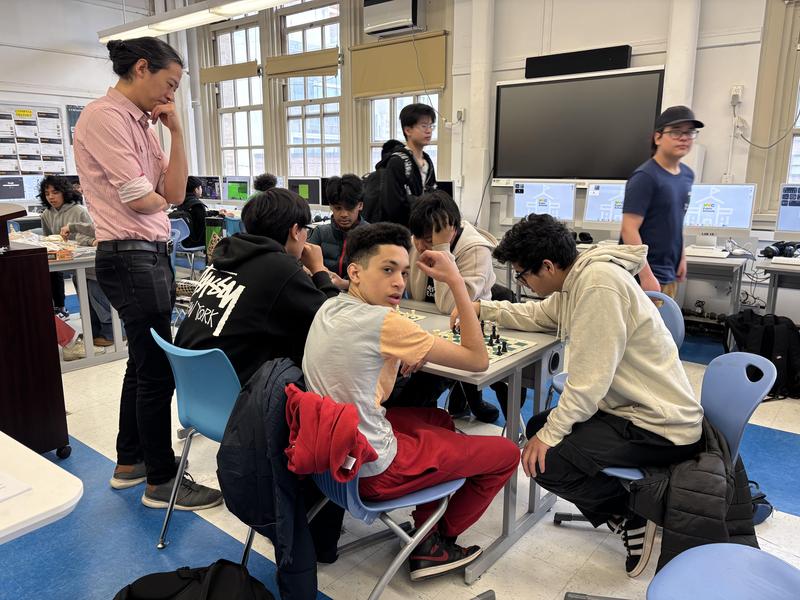Students engaged in chess games and group activities in a classroom setting.