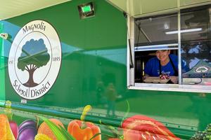 photo highlighting the positive and welcoming energy of a Food Services team member preparing to serve lunch from the District’s food truck.