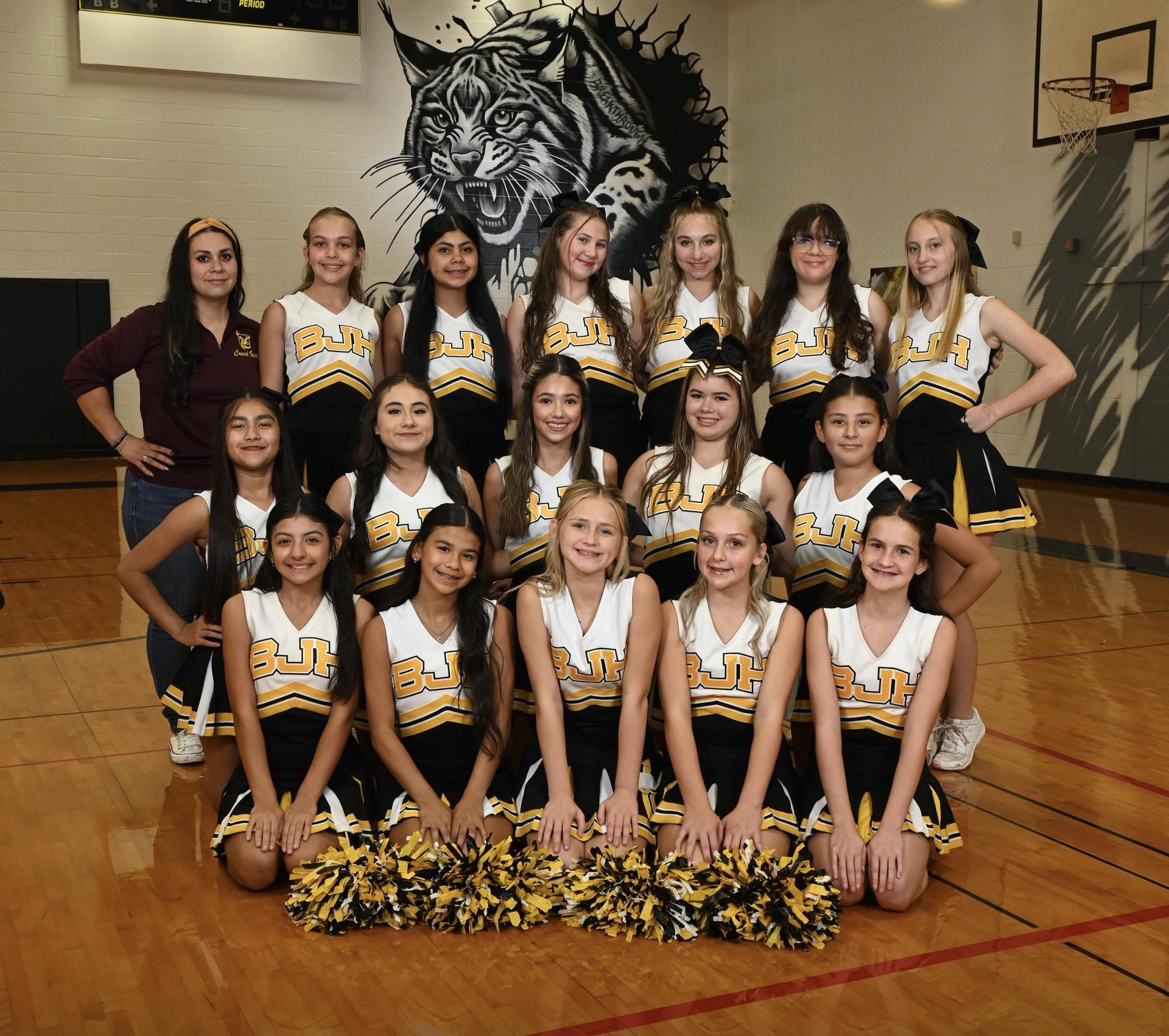 A group of cheerleaders posing for a picture in a school gym
