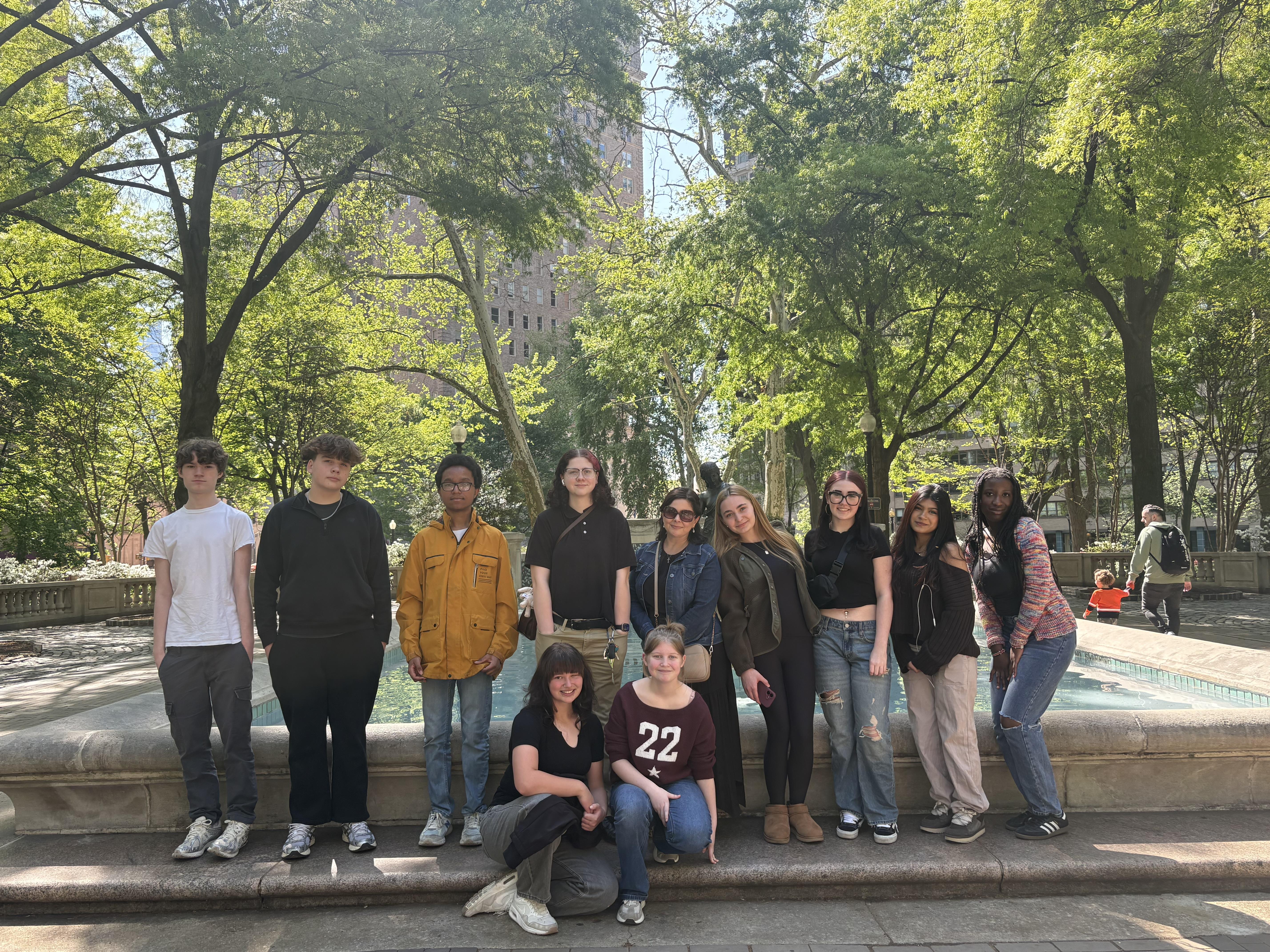 A group of smiling students with trees in the background.