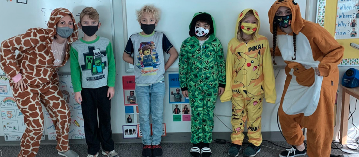 Students and teachers at Texas School for the Deaf (TSD) adapt to pandemic challenges during the first year of COVID-19. The image shows a group of children and two teachers wearing masks and creative, colorful costumes, including a giraffe, Minecraft, Pikachu, and other playful designs, demonstrating a fun and engaging approach to learning in a socially distanced classroom environment.