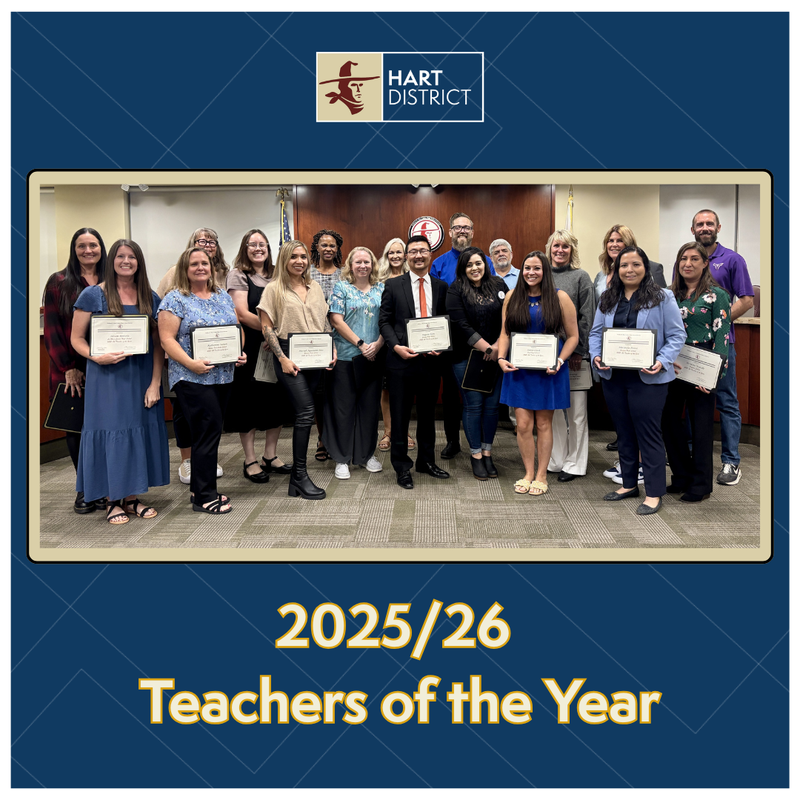 A group of teachers posing in the Hart District Board room smiling and holding certificates