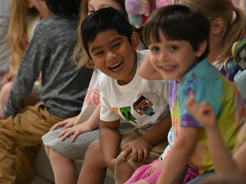 Two smiling children sitting together, enjoying a fun moment.