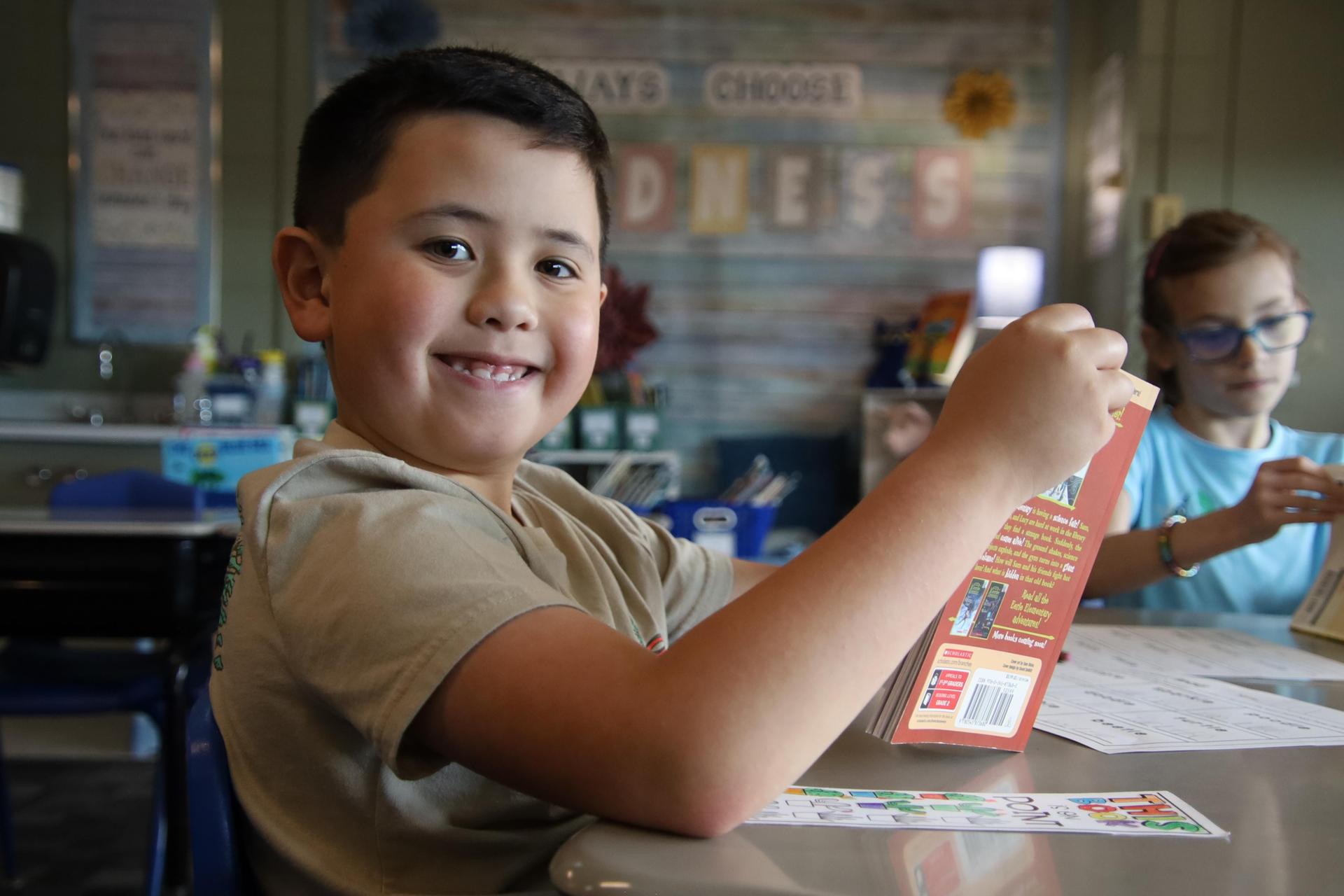 elementary school boy smiling for the camera in a classroom